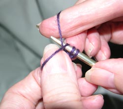 Figure 7.  With your first finger of your right hand – which is holding the ball end of yarn – bring the yarn over the point of the needle from the back.